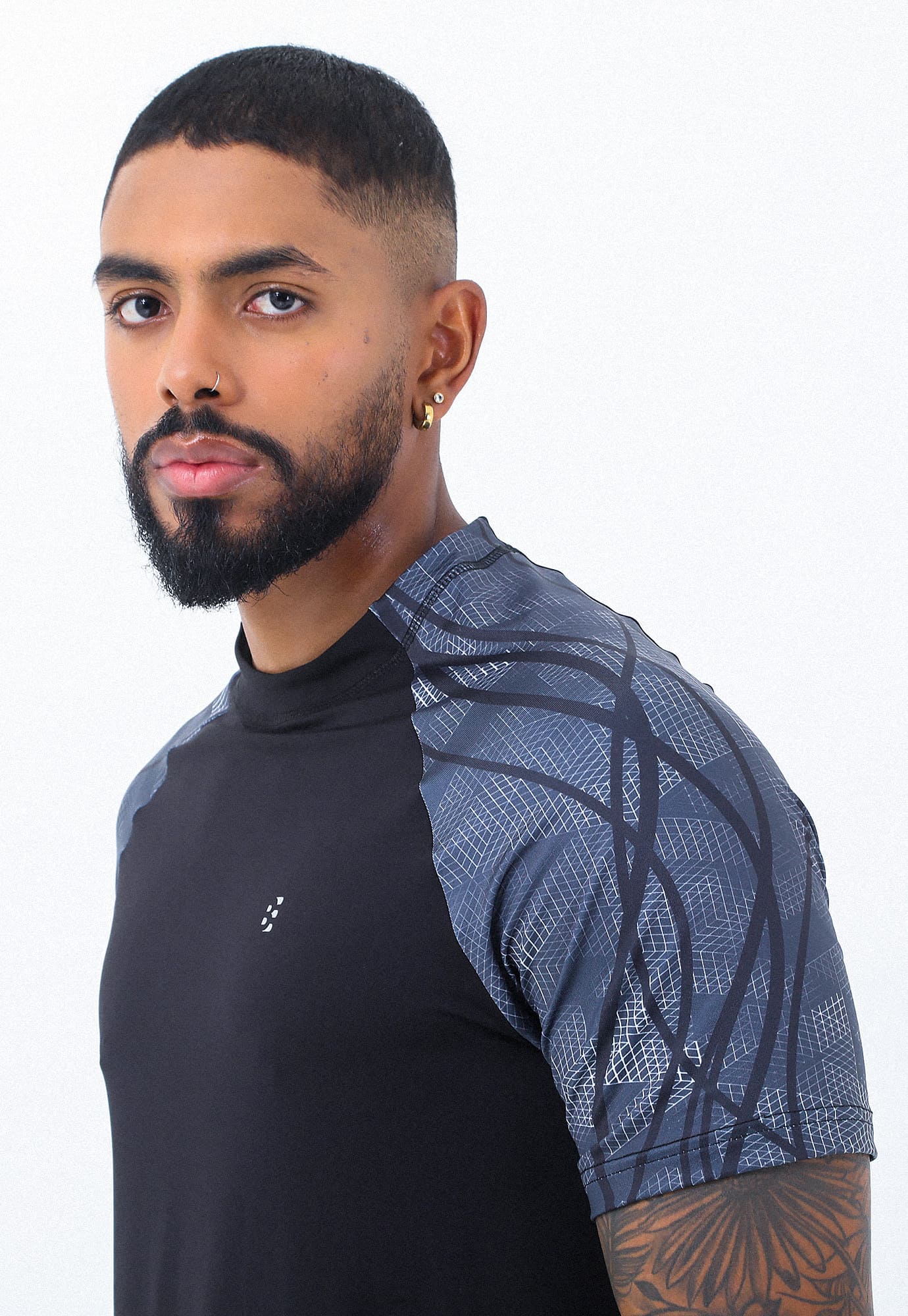Camiseta deportiva negra con mangas cortas tipo ranglán sublimadas y detalle reflectivo para hombre