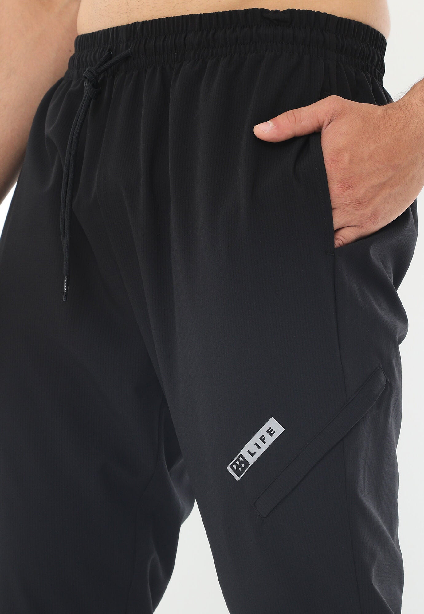 Pantalón deportivo negro tipo jogger con silueta ajustada, pretina con cordón ajustable y bolsillos laterales para hombre